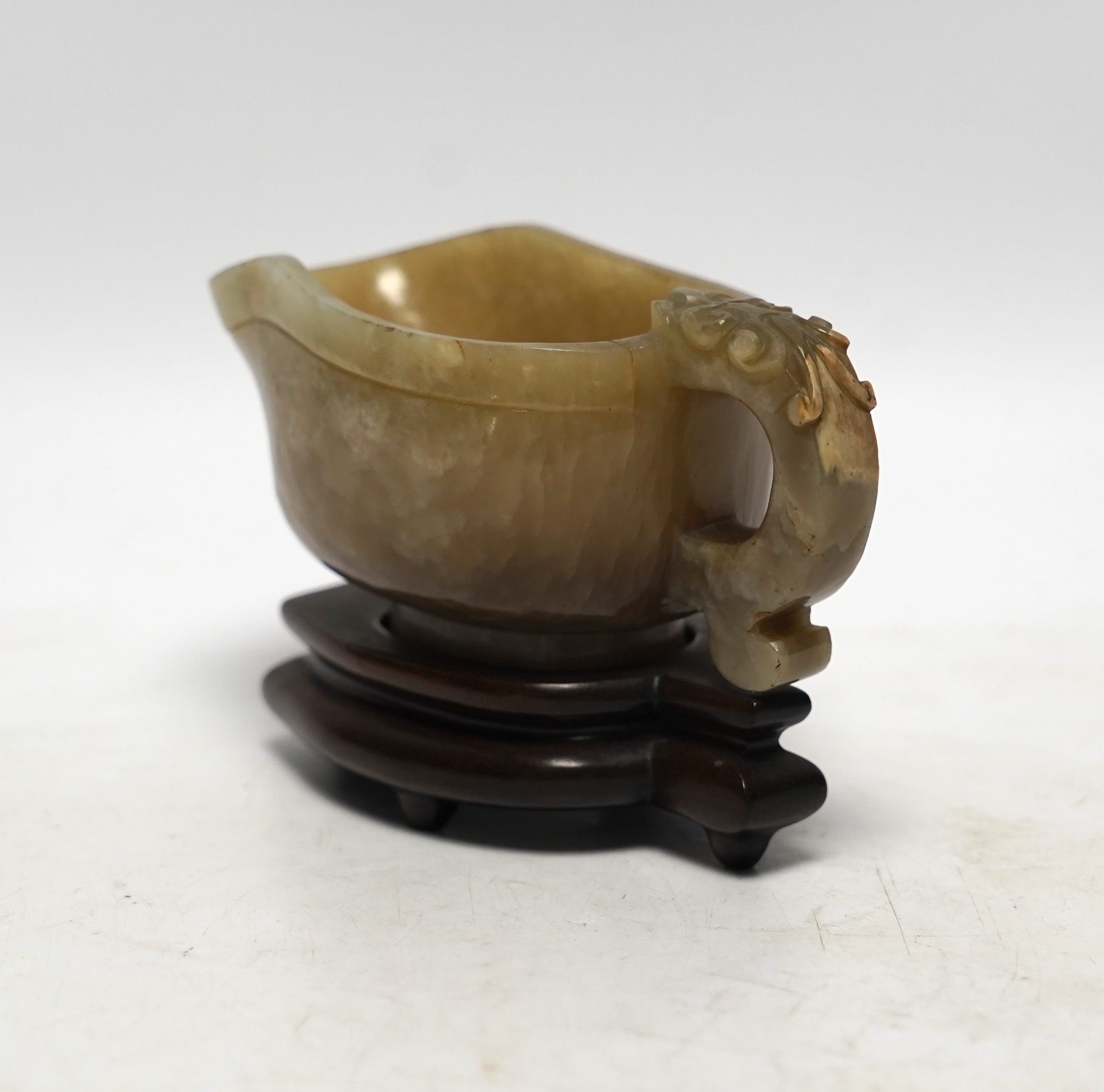 An 18th century Chinese archaistic jade pouring vessel, yi, with carved dragon handle, 6cm high, on a hardwood stand